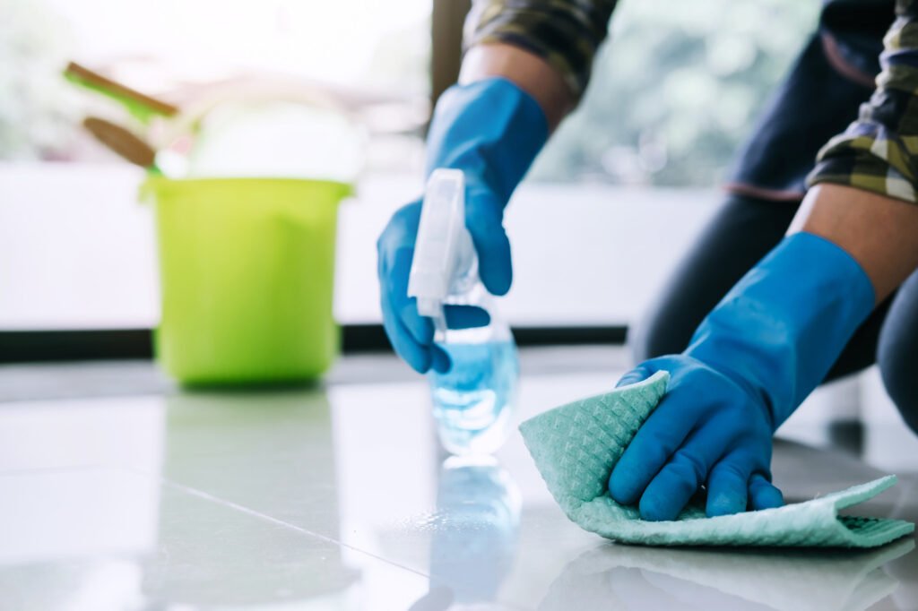 A person cleaning a floor with a sponge and cloth, demonstrating regular cleaning practices for a tidy environment.